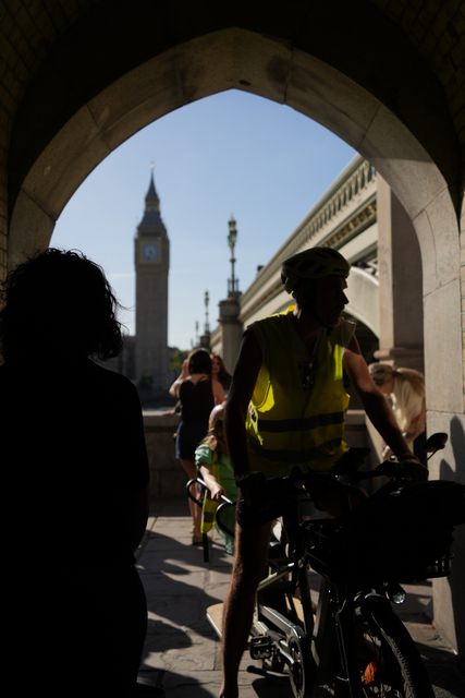 Cyclists in silhouette under a stone arch that frames Big Ben