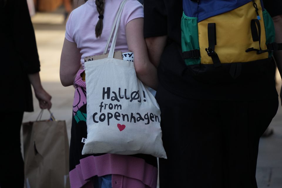 A tote bag reading "Hallo! from Copenhagen" between two people seen from behind
