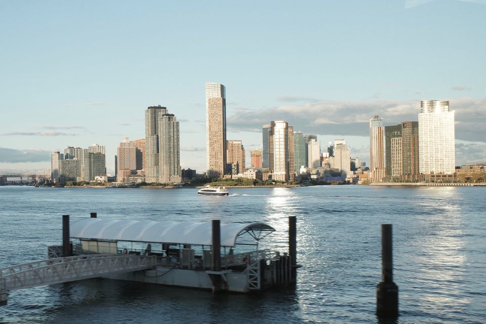 A ferry pier on a river with a waterfront skyline behind