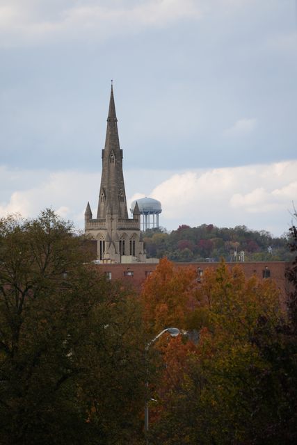 A church spire and a water tower above trees turning orange