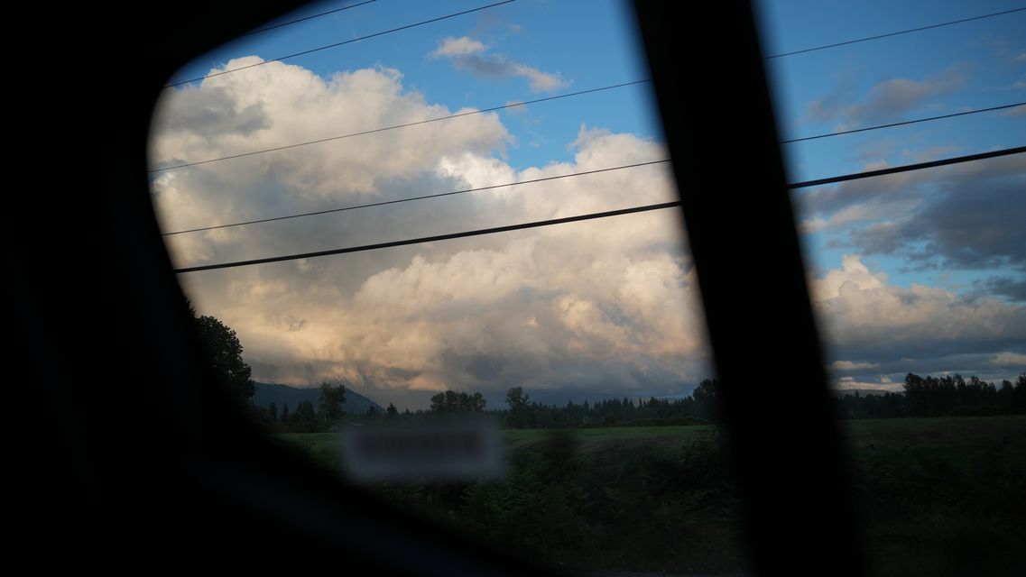 Evening clouds and power lines framed by a car window