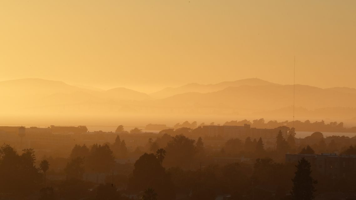 Layered hills and trees in orange haze at sunset