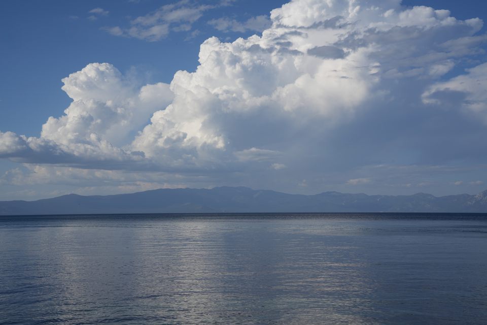 Towering clouds over a calm lake and a low line of mountains