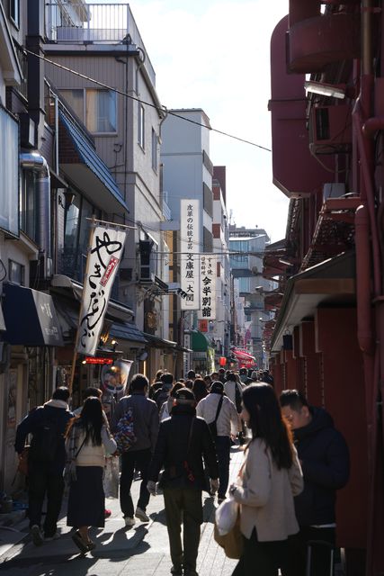 Pedestrians on a narrow shopping street hung with shop banners