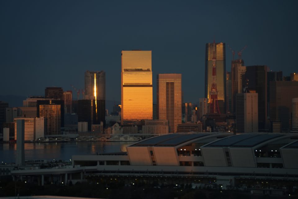 Skyscrapers catching the last gold light under a dark sky across the water