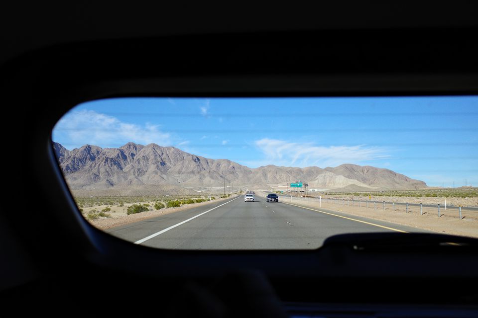 A desert highway and mountains seen through a car's rear window