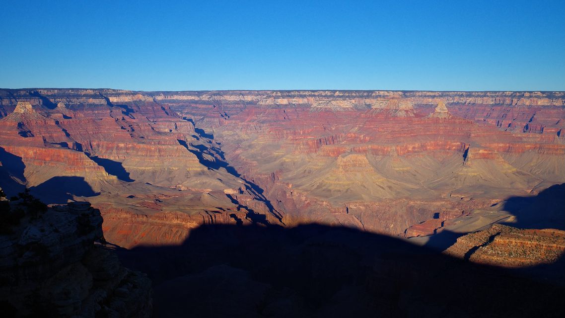 The Grand Canyon in layered red rock, the near rim in deep shadow