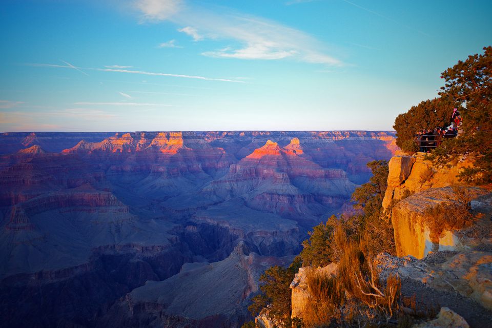 The Grand Canyon at sunset, an orange-lit cliff edge in the foreground
